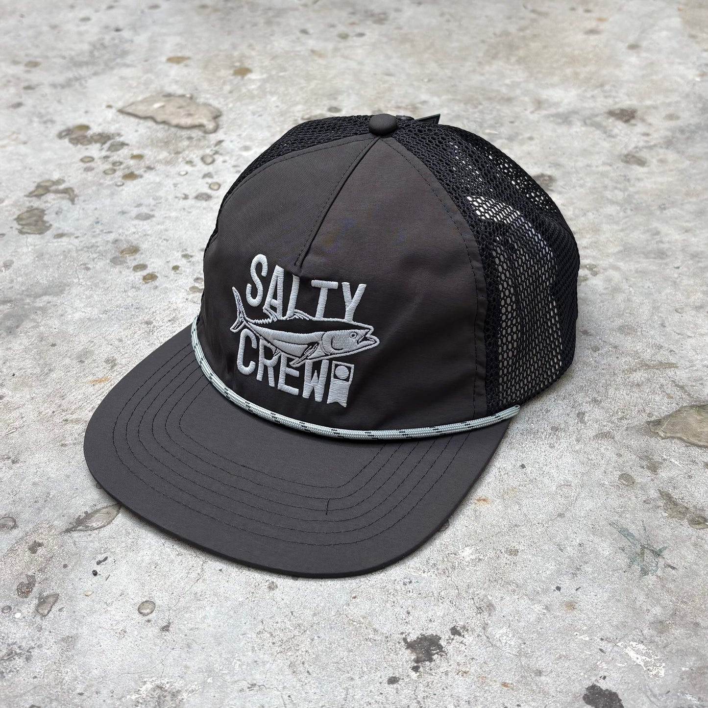 Black cap with 'Salty Crew' logo on a concrete surface
