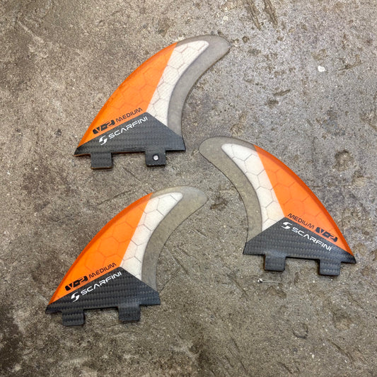 Three orange and gray archery nocks on a concrete surface