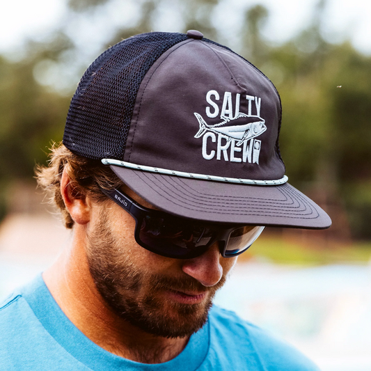 Man wearing a Salty Crew cap and sunglasses with a blurred natural background