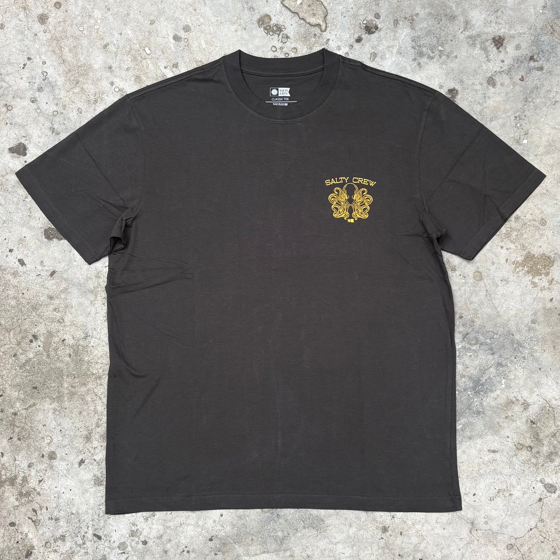 Black t-shirt with yellow logo on a textured gray surface