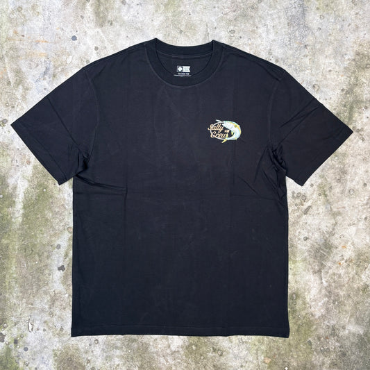 A black short-sleeve crewneck t-shirt with a small multicolor graphic on the left chest, laid flat on a textured concrete surface.