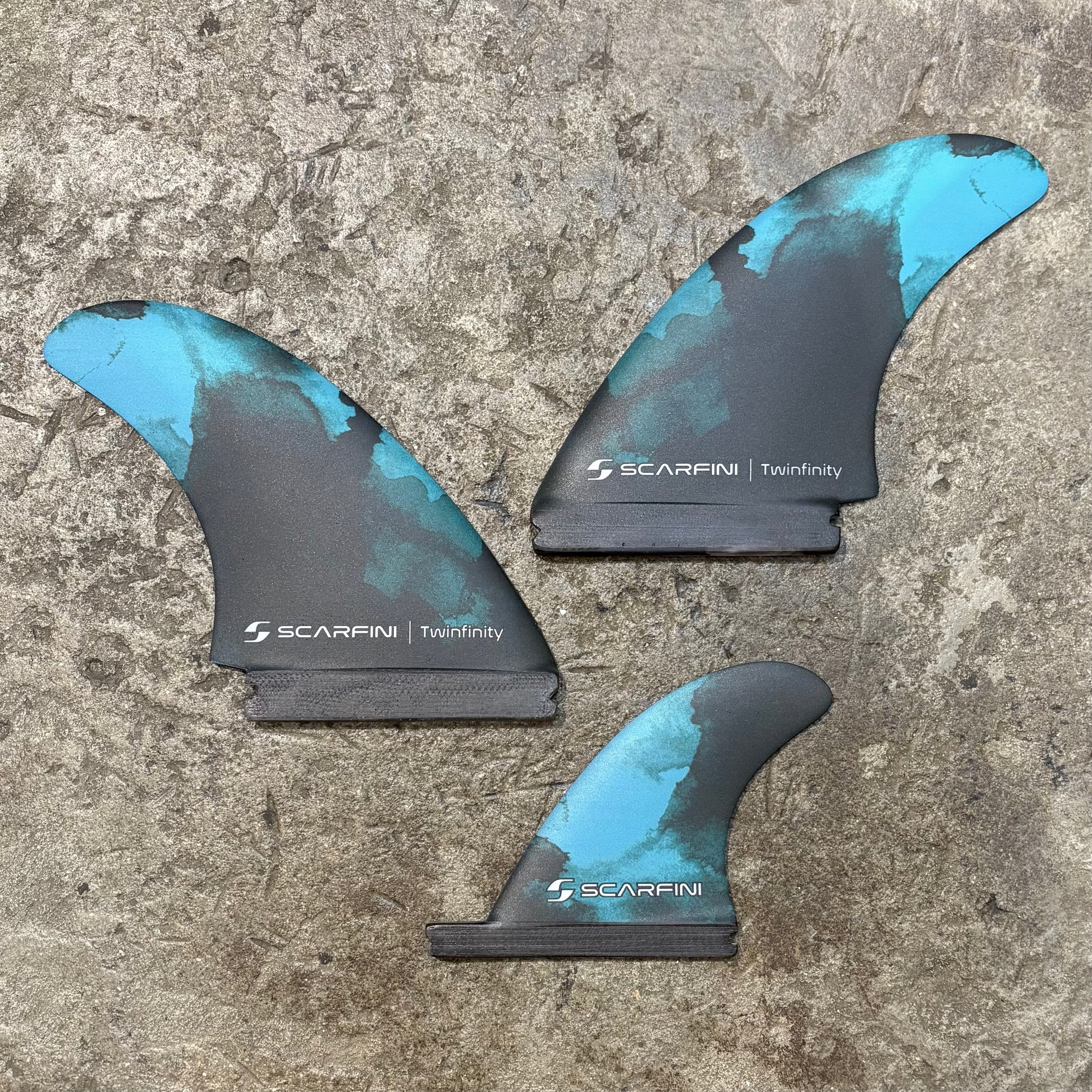Set of Scarfini Twin Fin | Single Tab + Stabilizer on a concrete floor