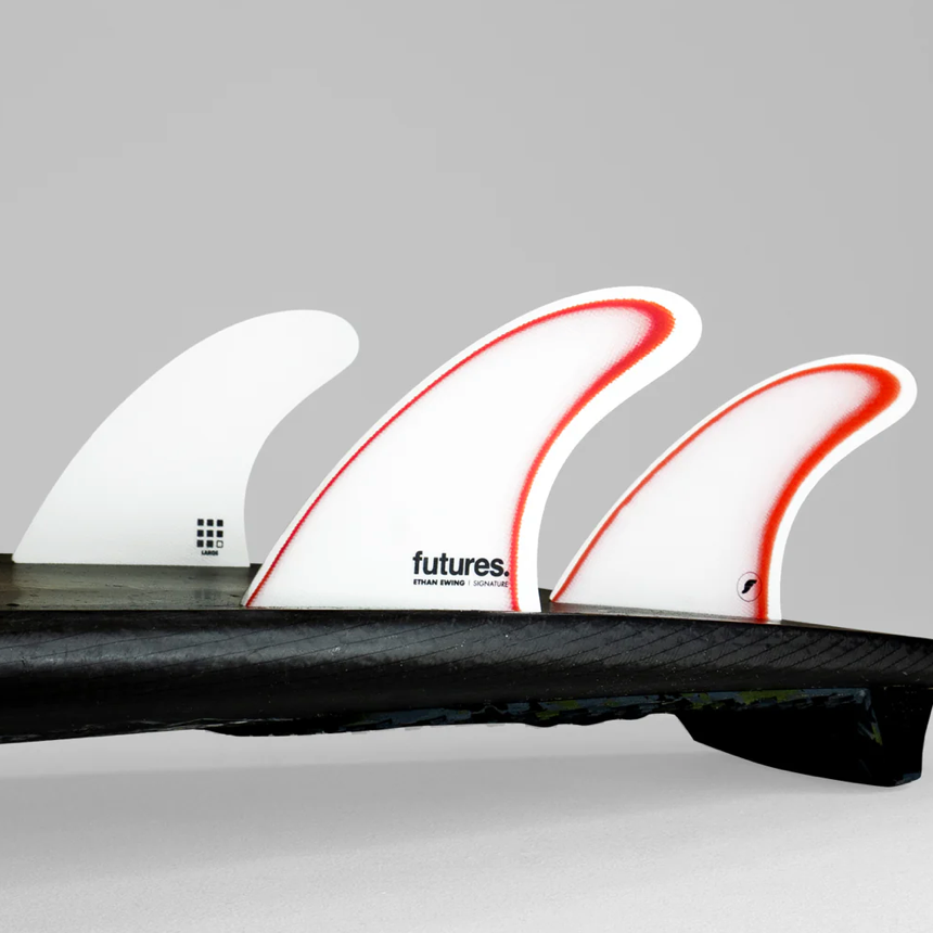 Three surfboard fins with 'futures' branding on a gray background