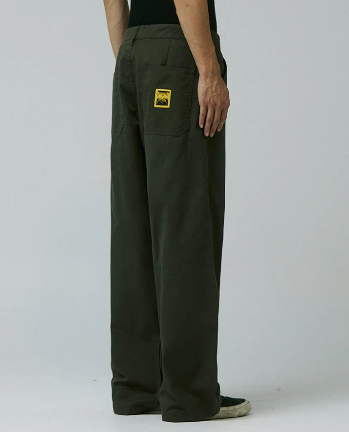 Dark green pants with a patch on a plain background