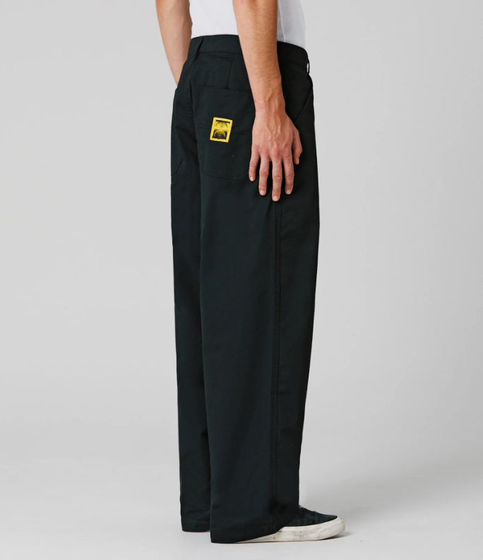 Person wearing black pants with a yellow logo on a gray background