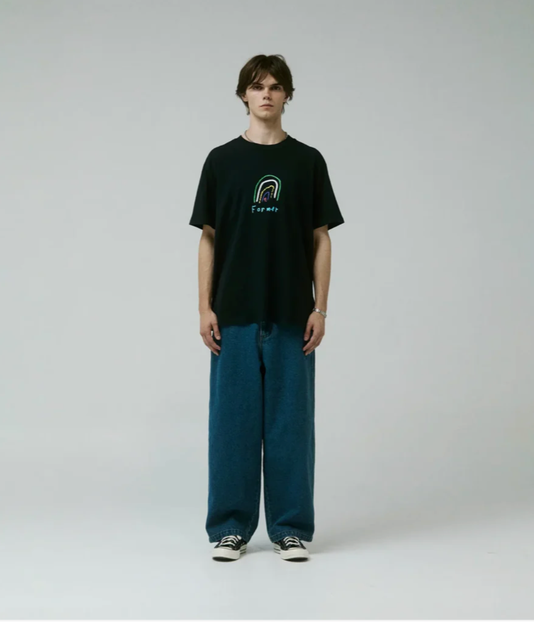 Person wearing a black t-shirt with a logo and blue jeans on a white background