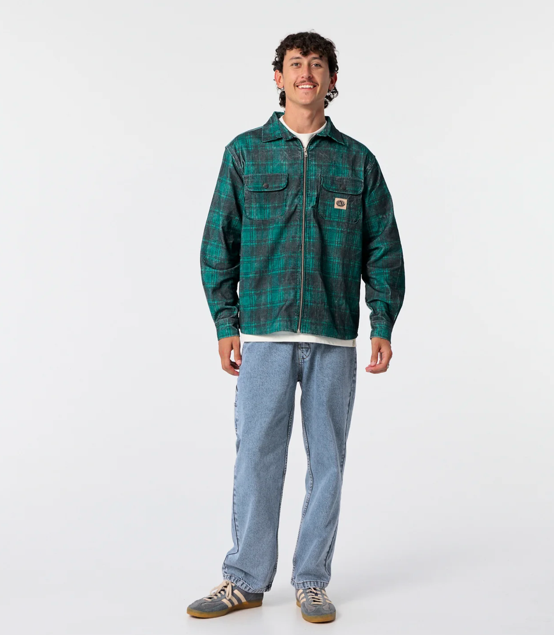 Man wearing a green plaid shirt and blue jeans on a white background