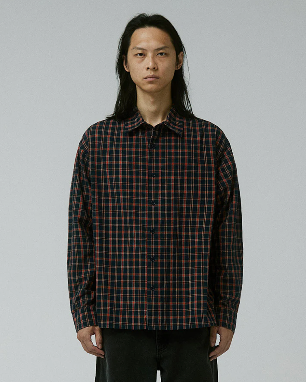 Person wearing a plaid shirt against a plain background