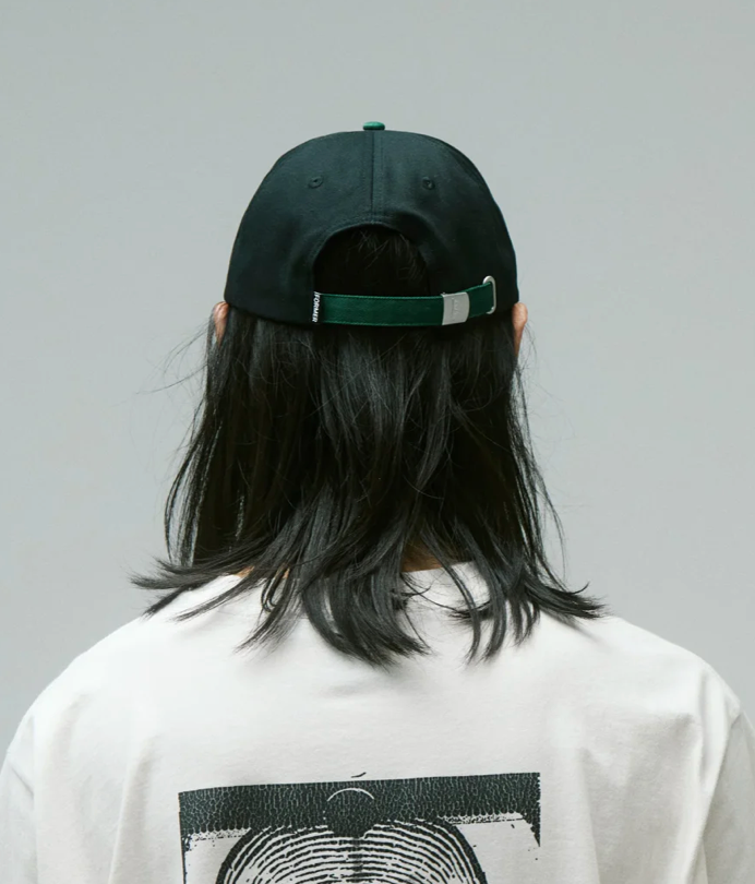 Person wearing a black cap and white shirt with graphic design on a gray background