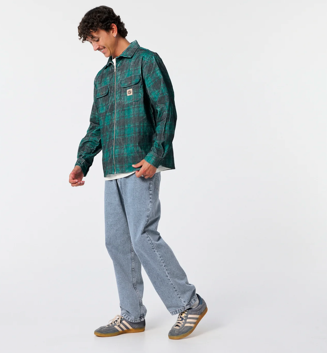 Person wearing a green plaid shirt and blue jeans on a white background
