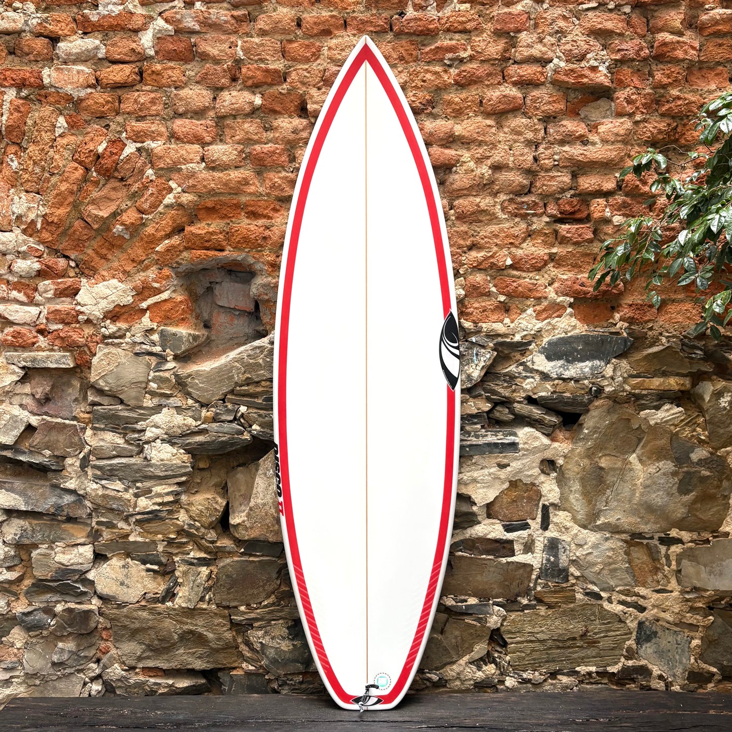 Sharp Eye Surfboards   Disco ll   5'10" x 20.0 x 2.58 31.30 L in front of a a rustic wall