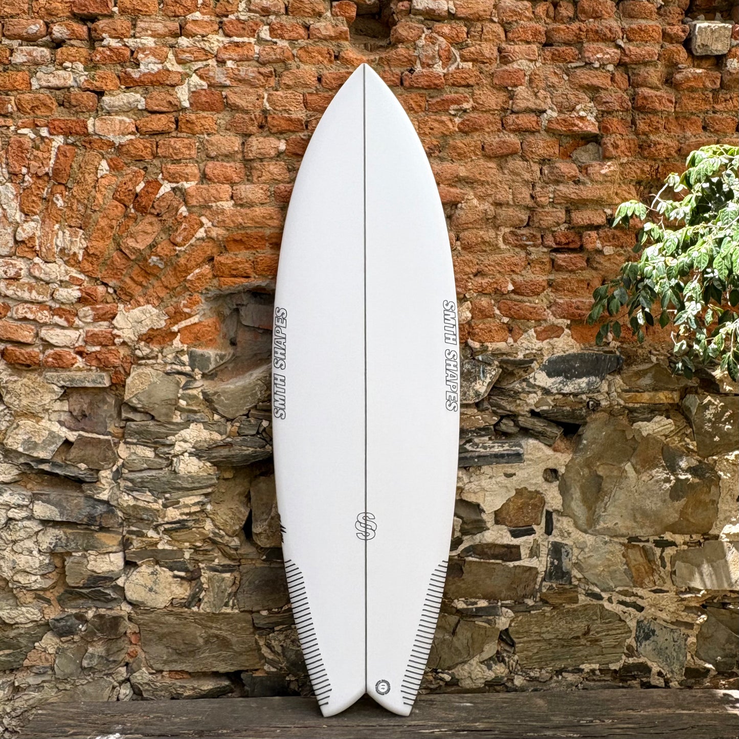 Smth Shapes Speed Demon Surfboard   in front of a brick wall