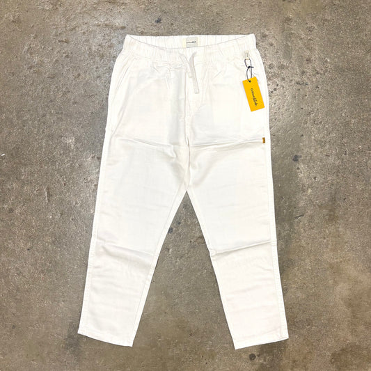 White pants with a yellow tag on a concrete floor