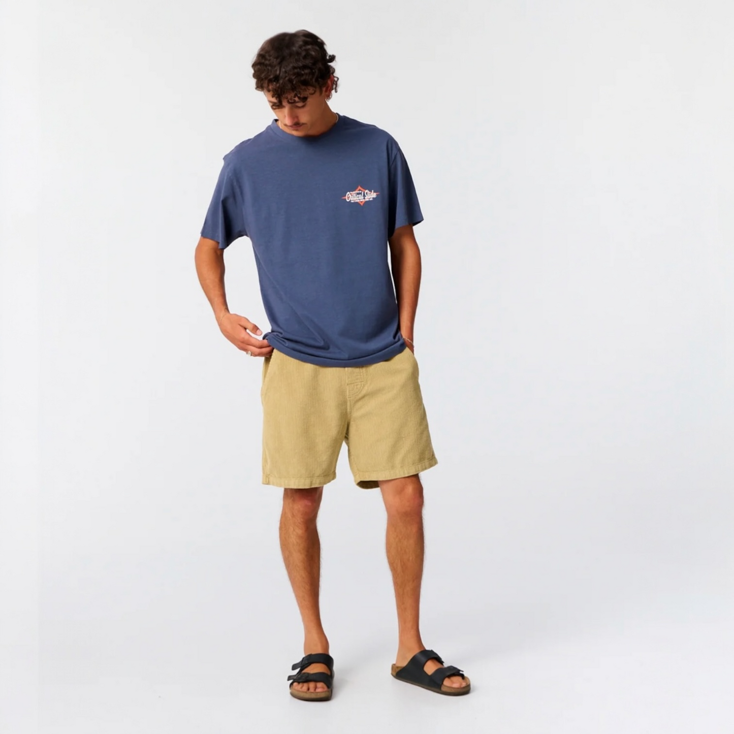 Person wearing a blue t-shirt and beige shorts on a white background