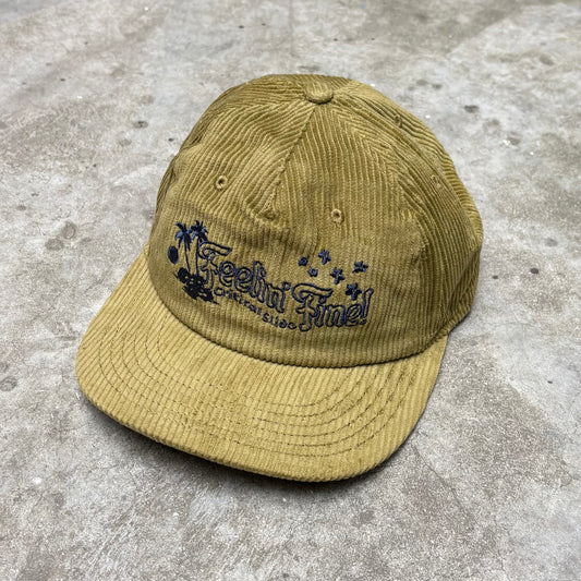 Beige cap with 'Feelin Fine' text on a concrete surface