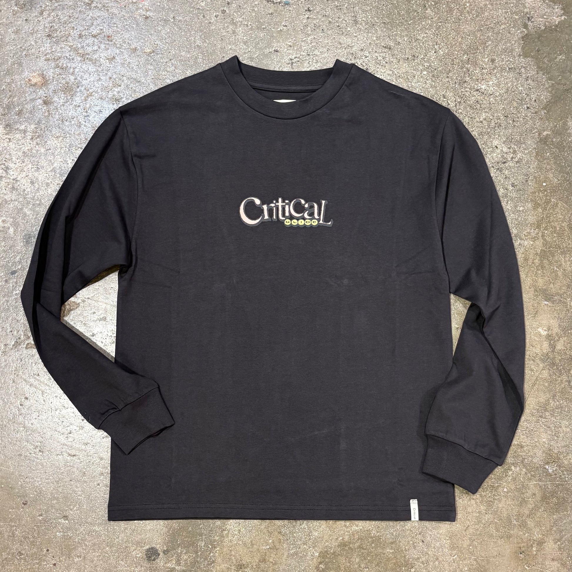 Black long-sleeve shirt with 'Critical' logo on a concrete surface