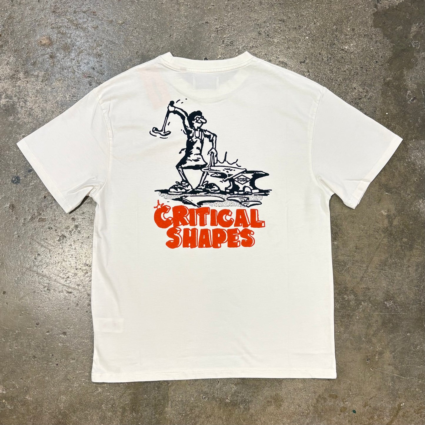 White t-shirt with black and red graphic design on a concrete surface