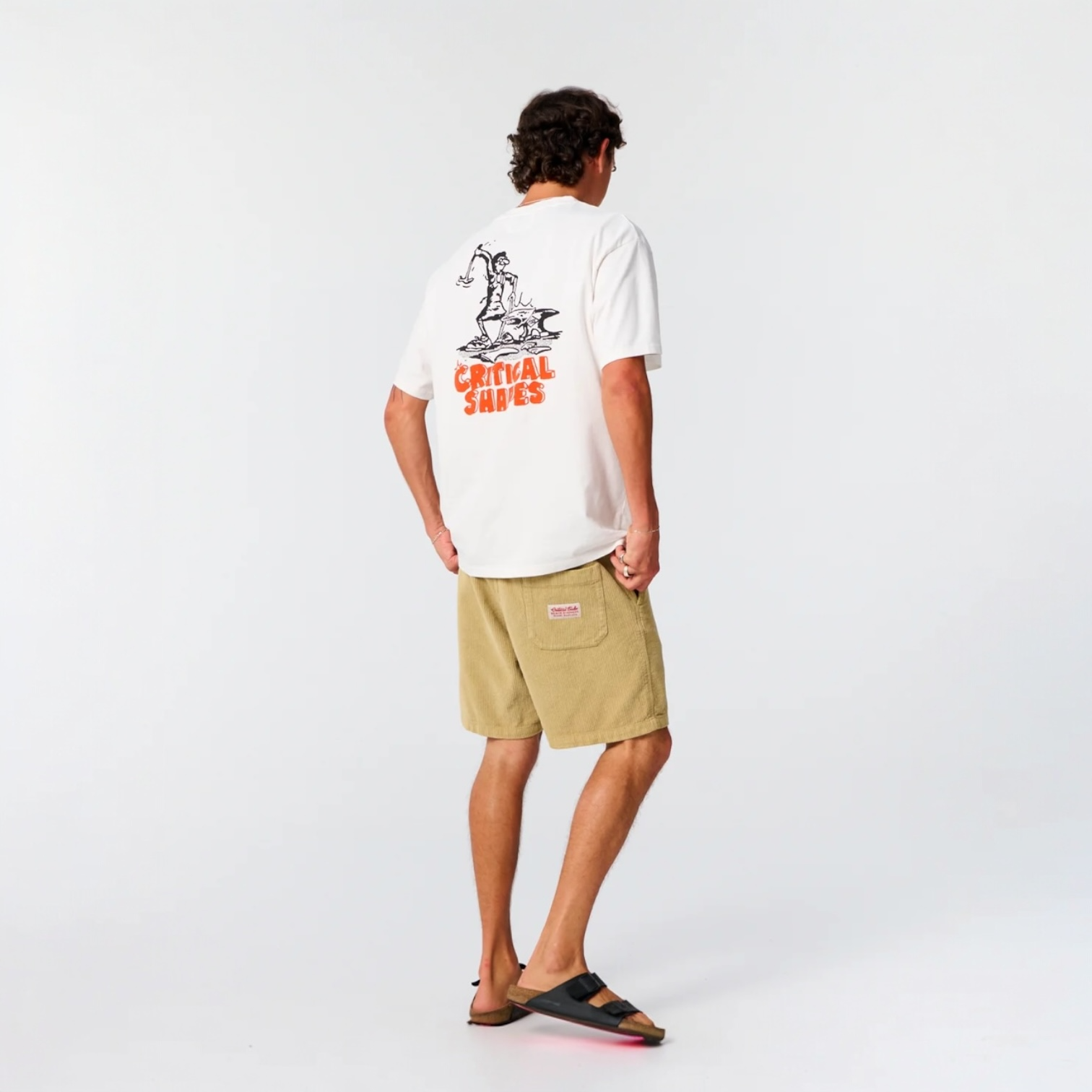 Person wearing a white t-shirt with graphics and text, standing against a plain background