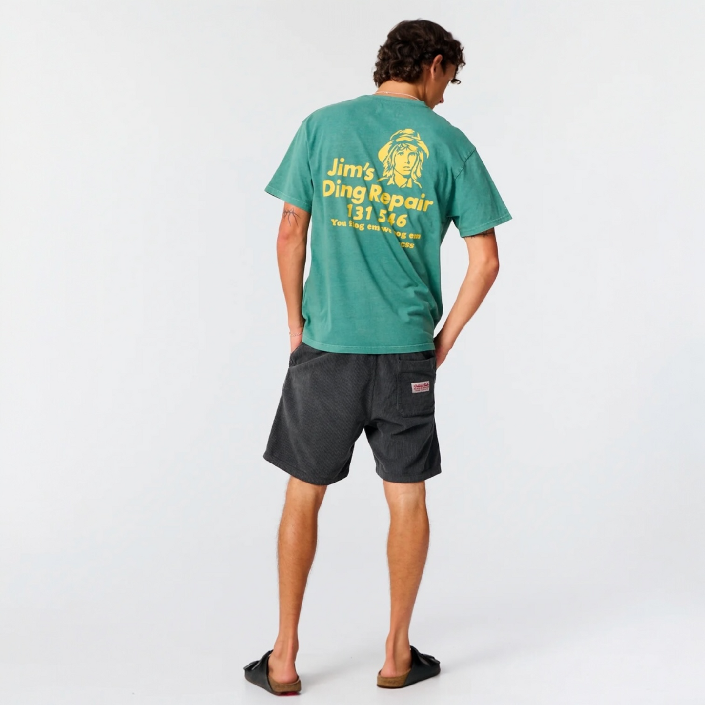 Person wearing a green t-shirt with yellow text and graphics on a white background