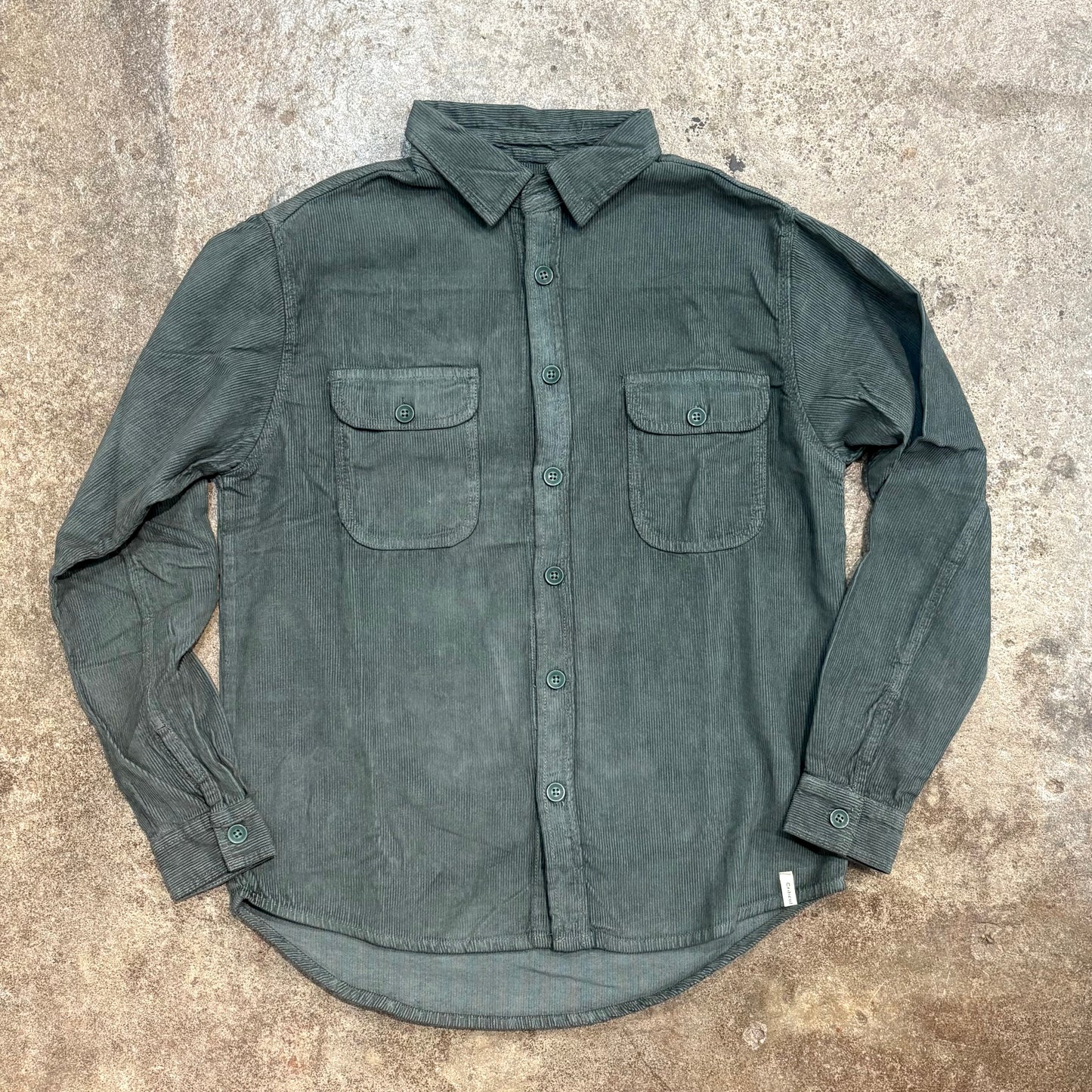 Green button-up shirt on a textured surface