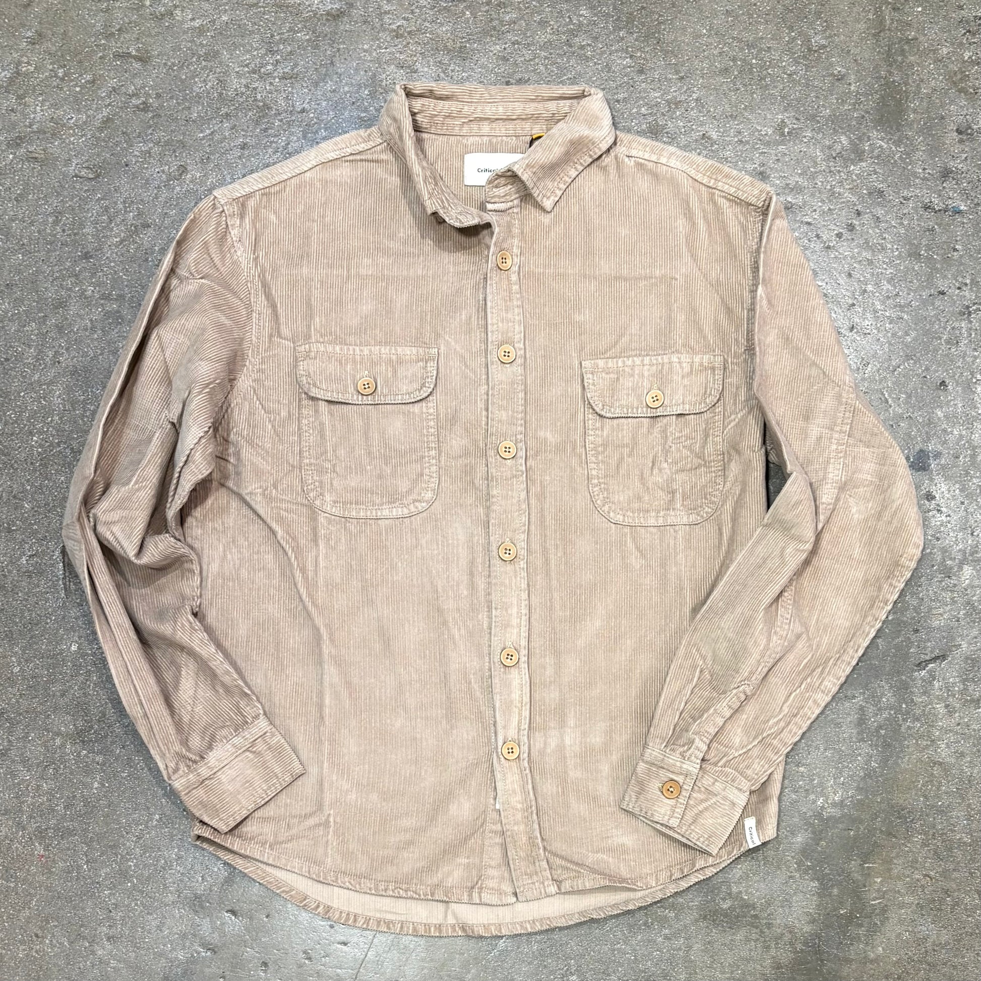 Beige button-up shirt on a gray concrete surface