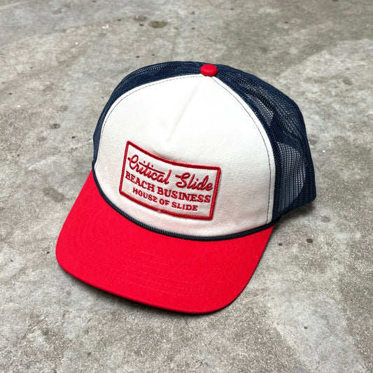 Red and white cap with a logo on a concrete surface