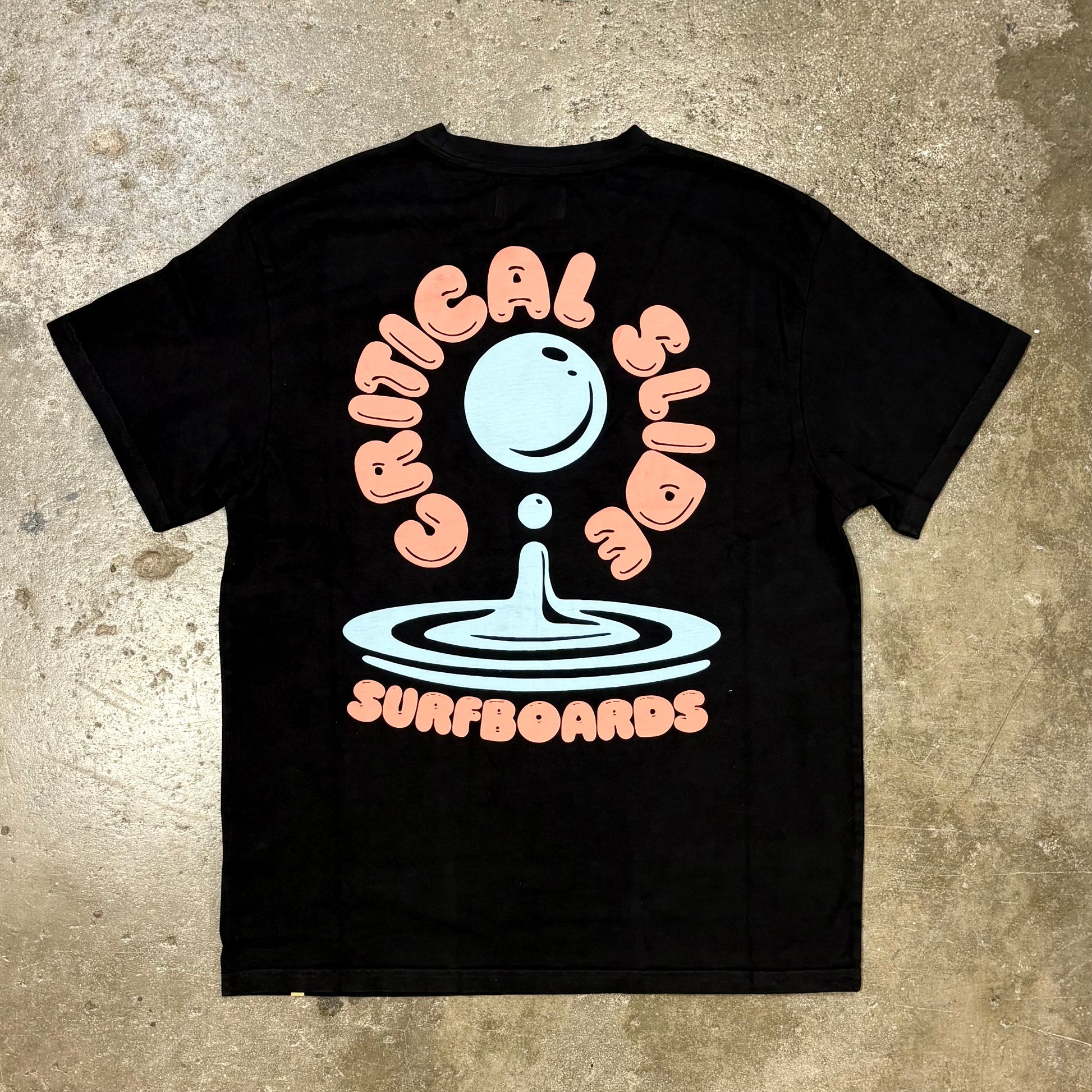 Black t-shirt with 'Critical Slide Surboards' graphic on a textured surface