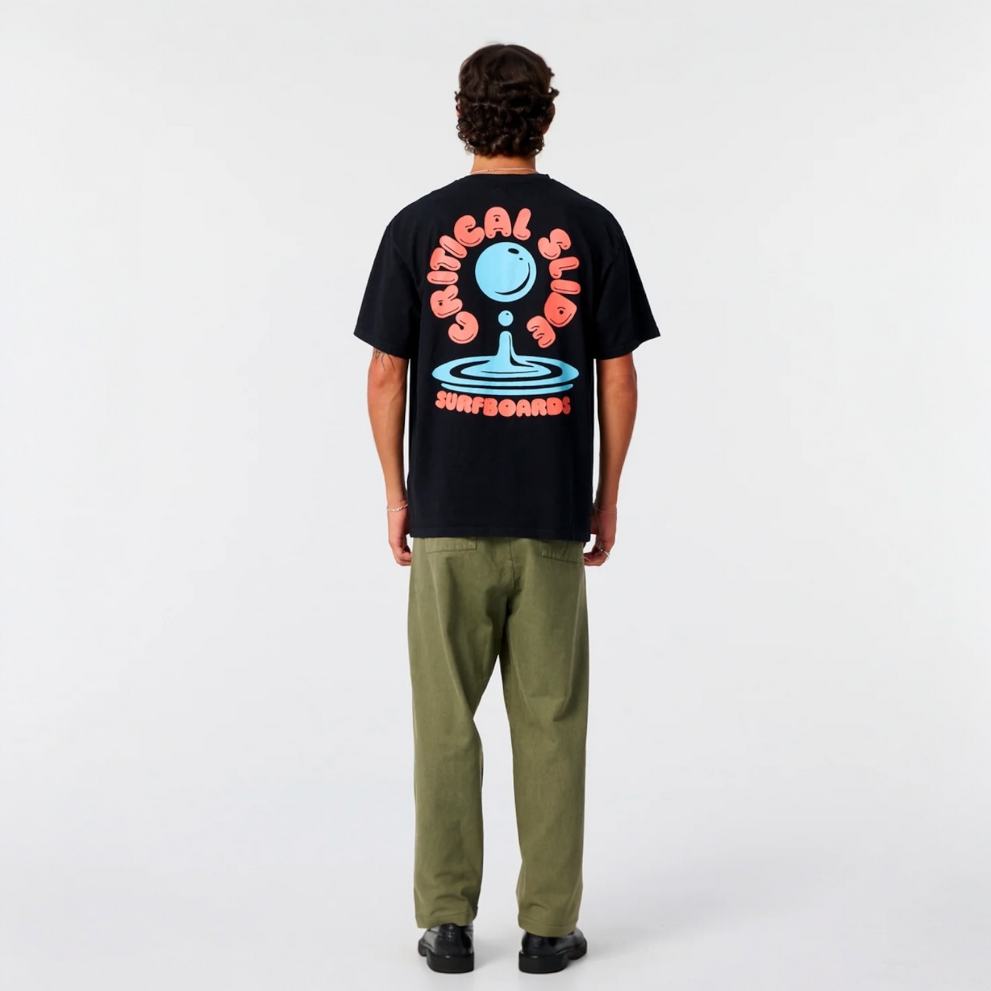 Person wearing a black t-shirt with a colorful graphic on the back, standing against a white background
