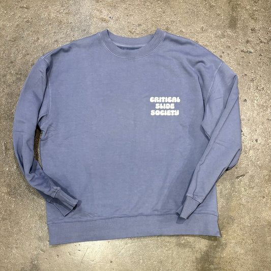Blue sweatshirt with 'Critical Slide Society' text on a concrete surface