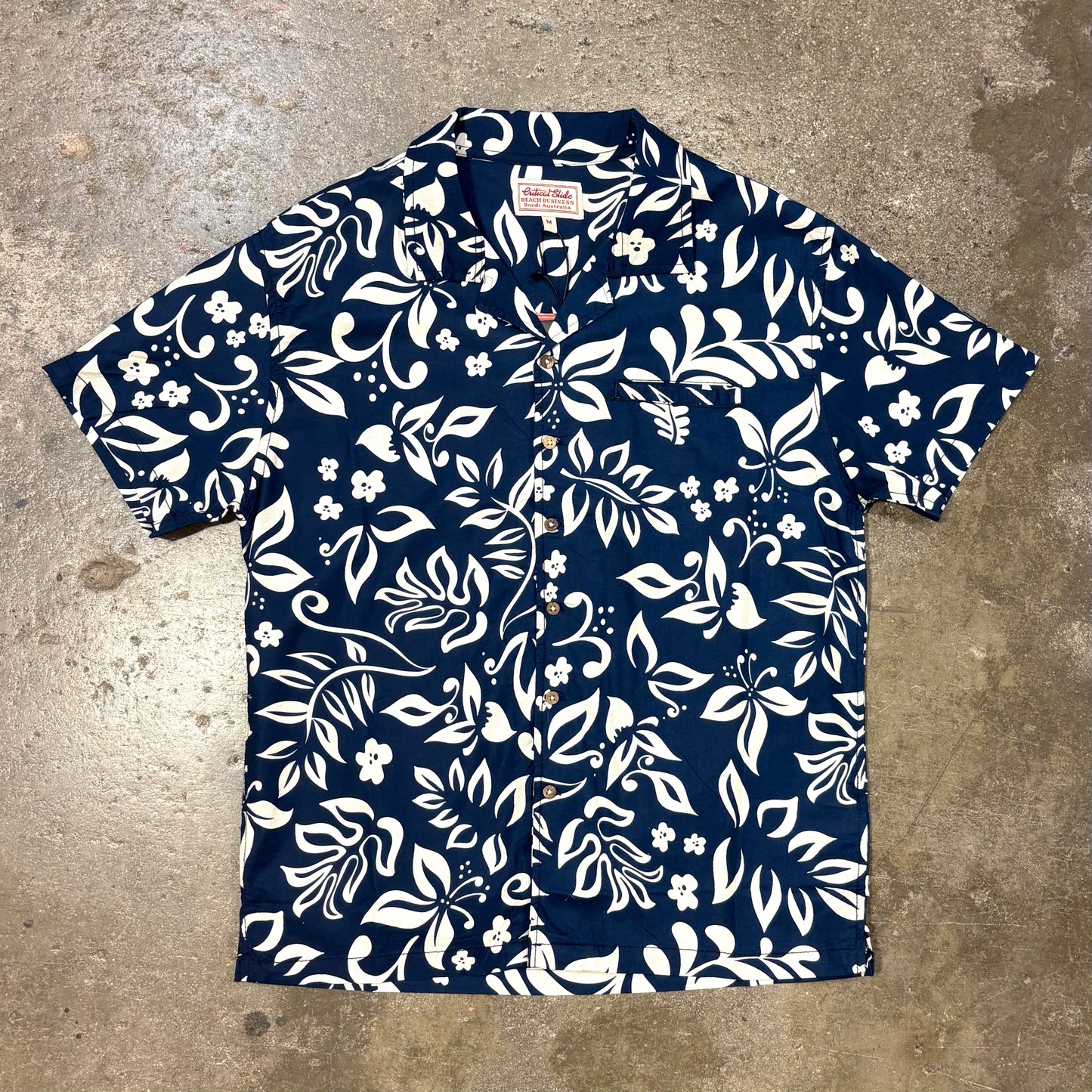 Navy blue shirt with white floral pattern on a concrete surface