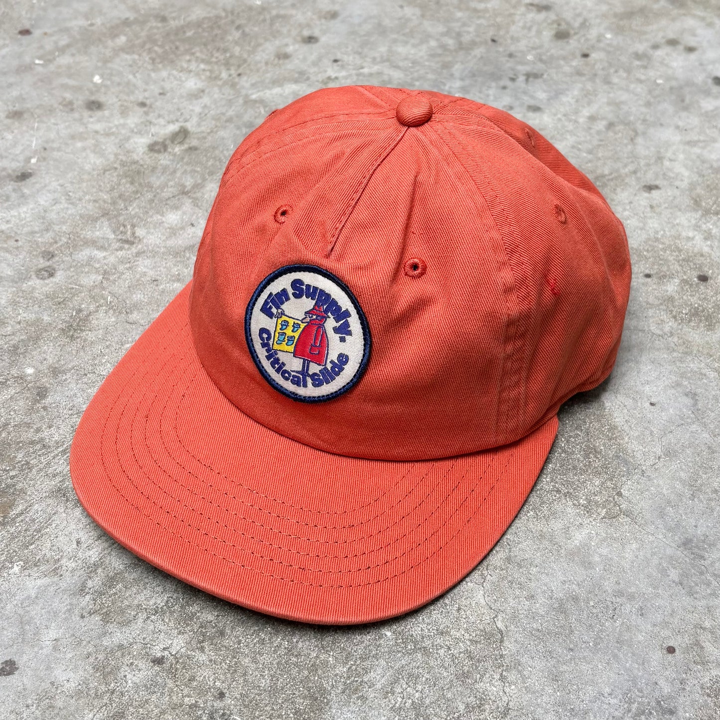 Orange cap with a logo on a concrete surface