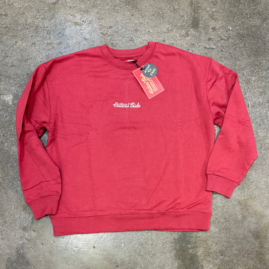 Red sweatshirt with a tag on a gray concrete surface