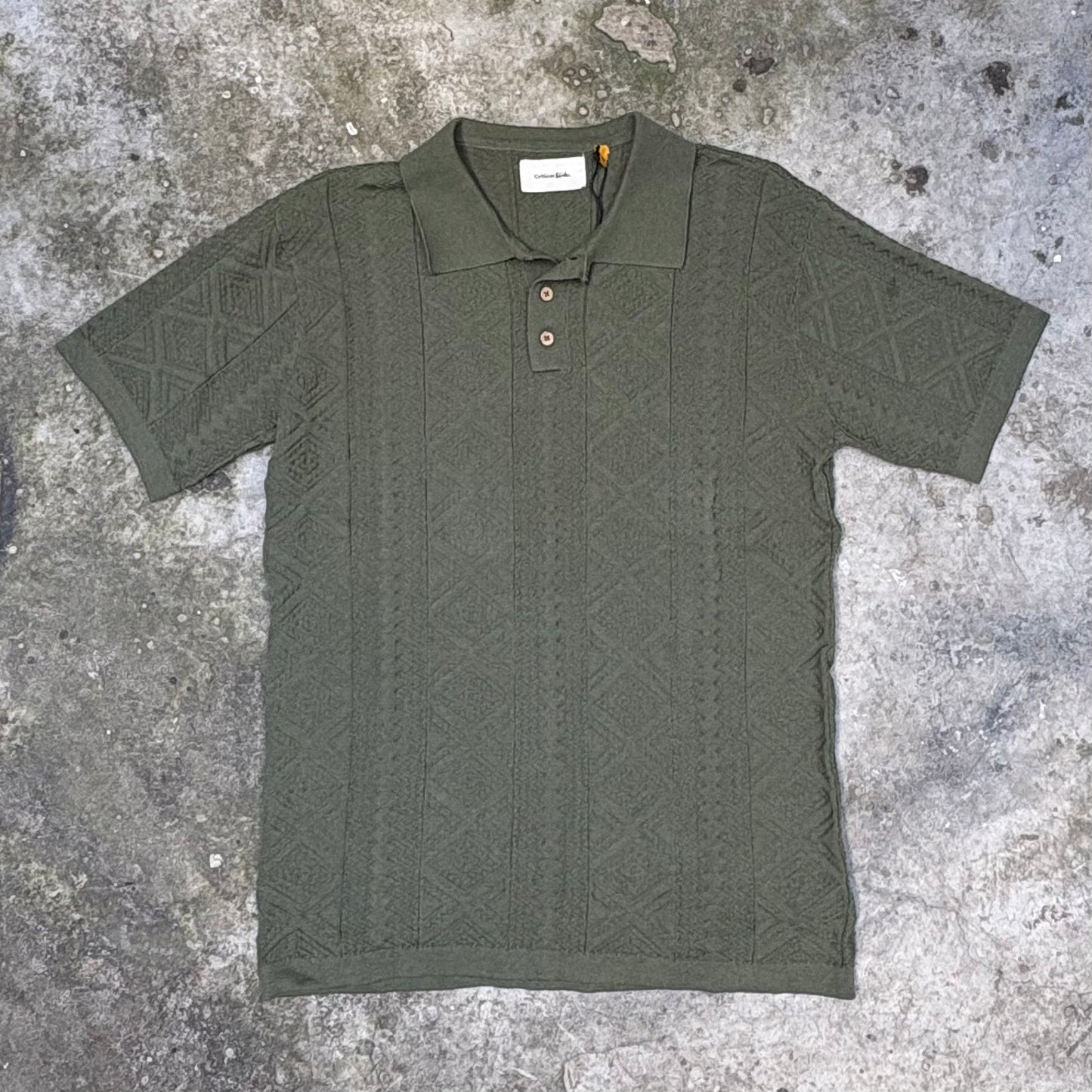 Green patterned polo shirt on a textured gray surface