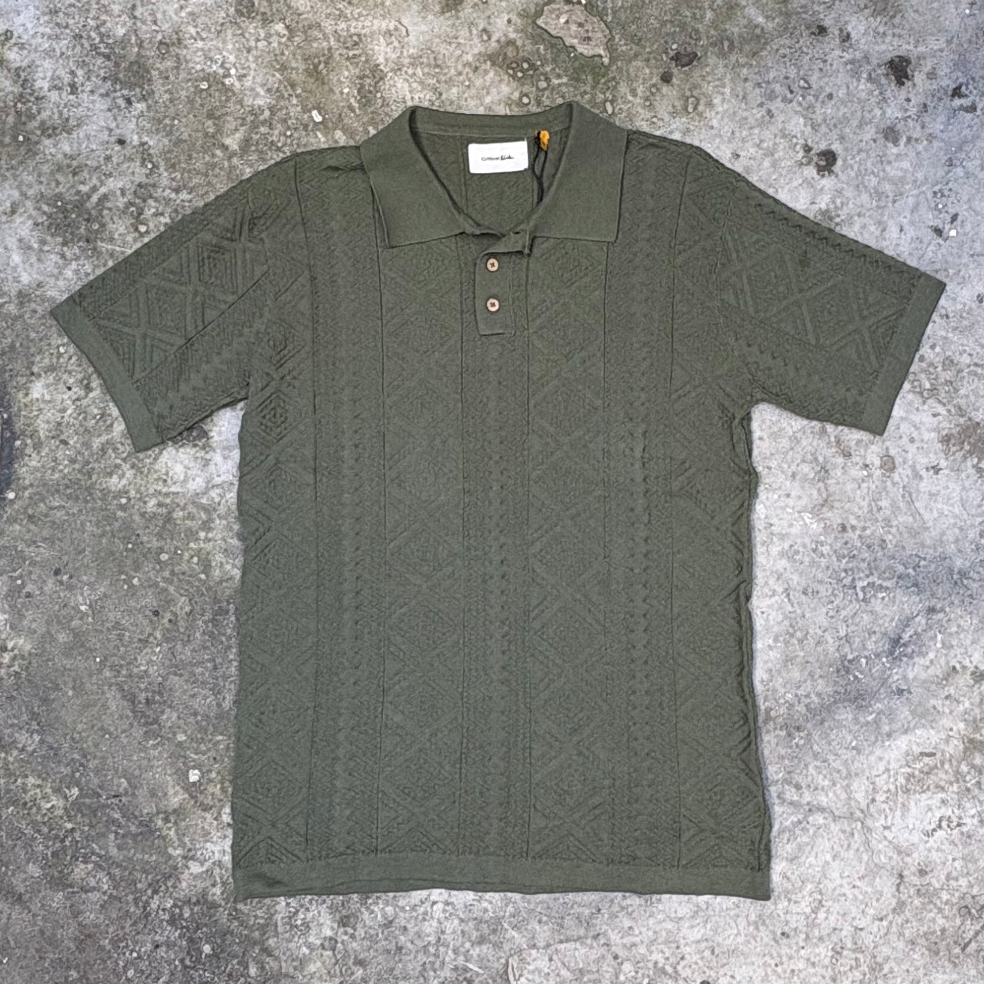 Green patterned polo shirt on a textured gray surface