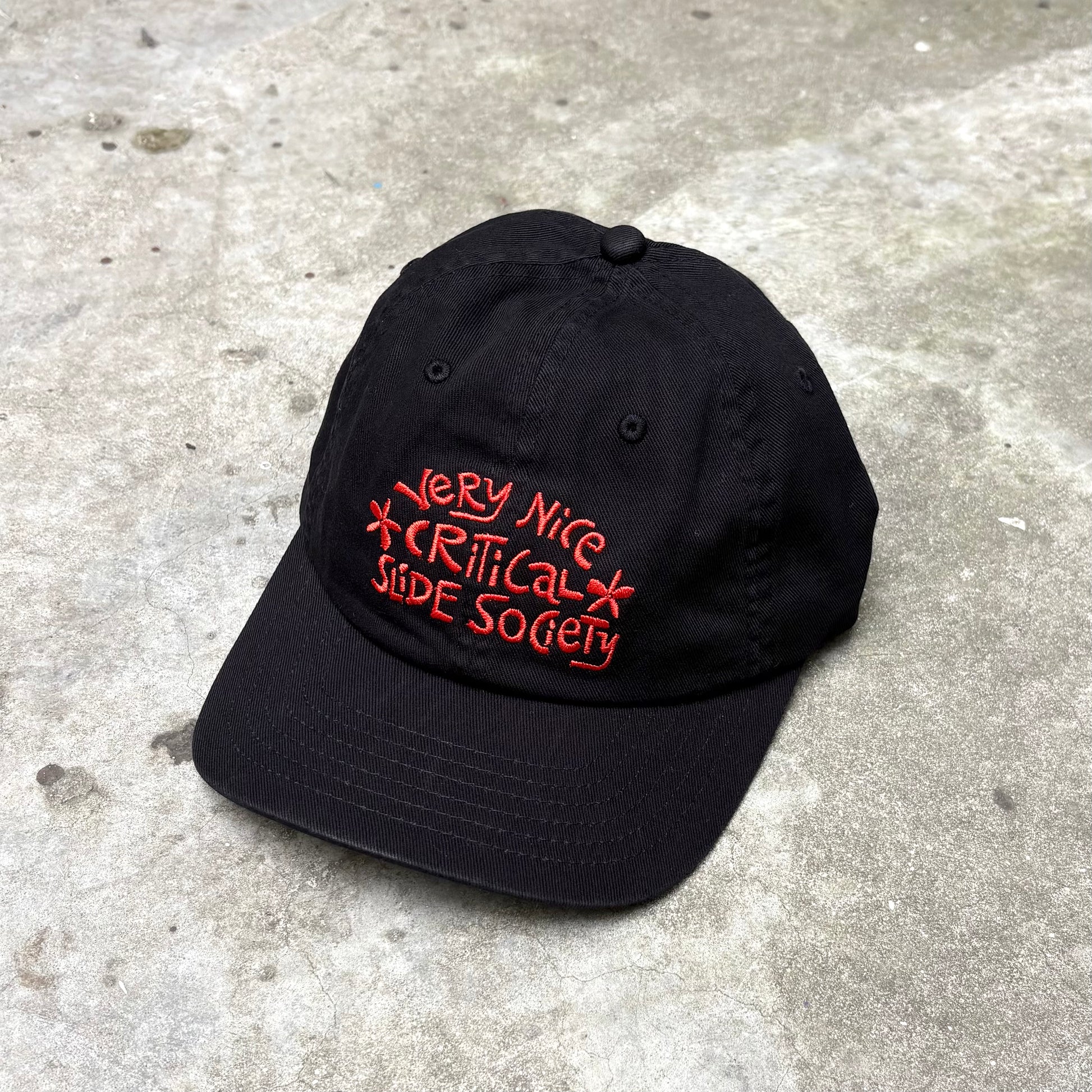Black cap with red text on a concrete surface