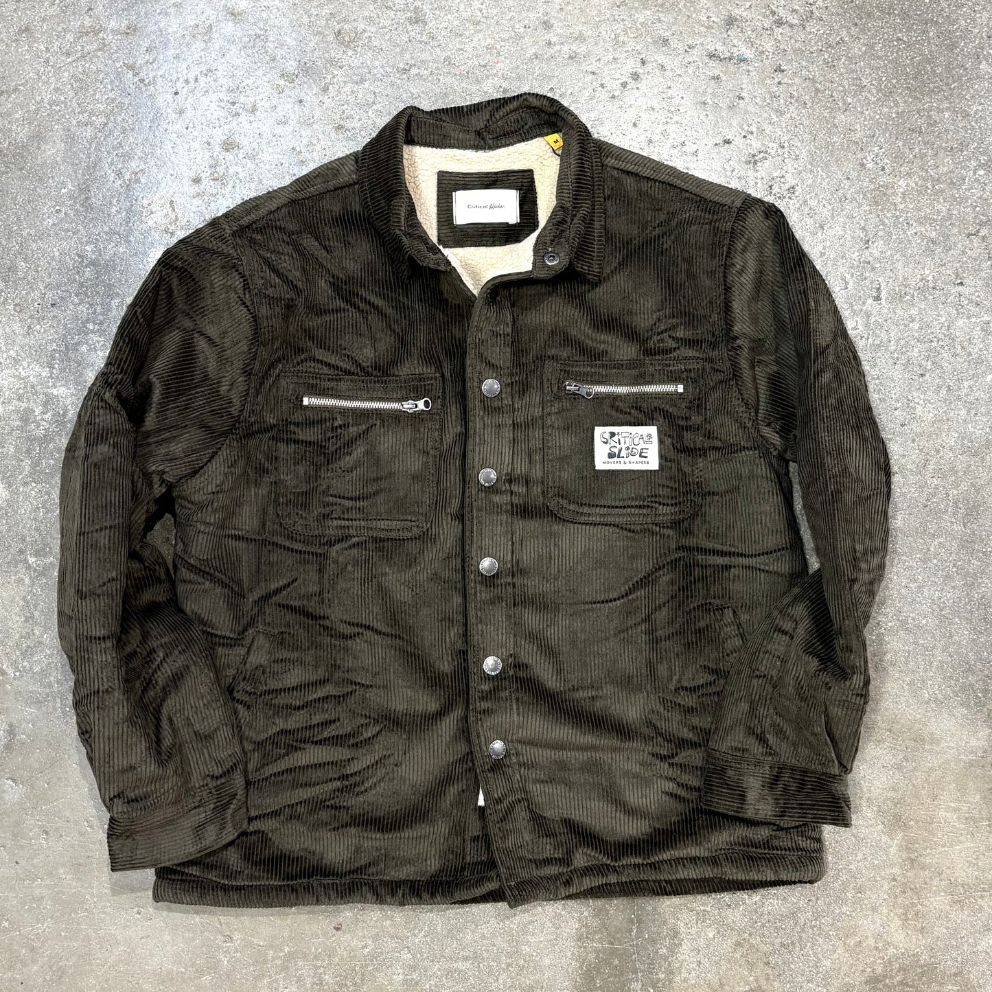 Dark green jacket with zippers and buttons on a gray textured background