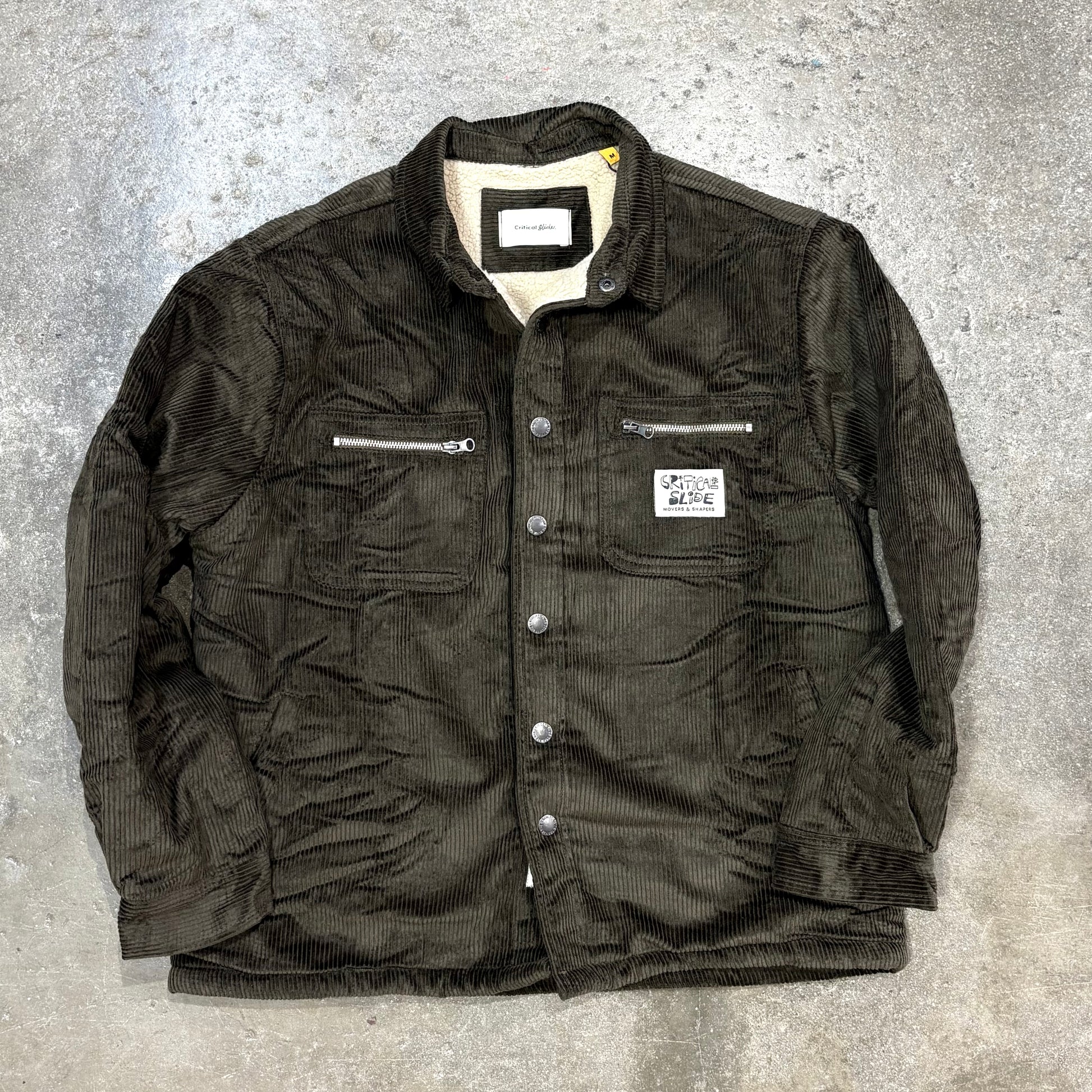 Dark green jacket with zippers and buttons on a gray textured background