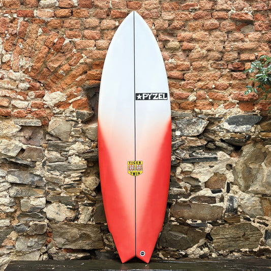 TIGER TWIN    5'6"    20"    2.56"    31L Surfboard with a gradient design against a stone wall.