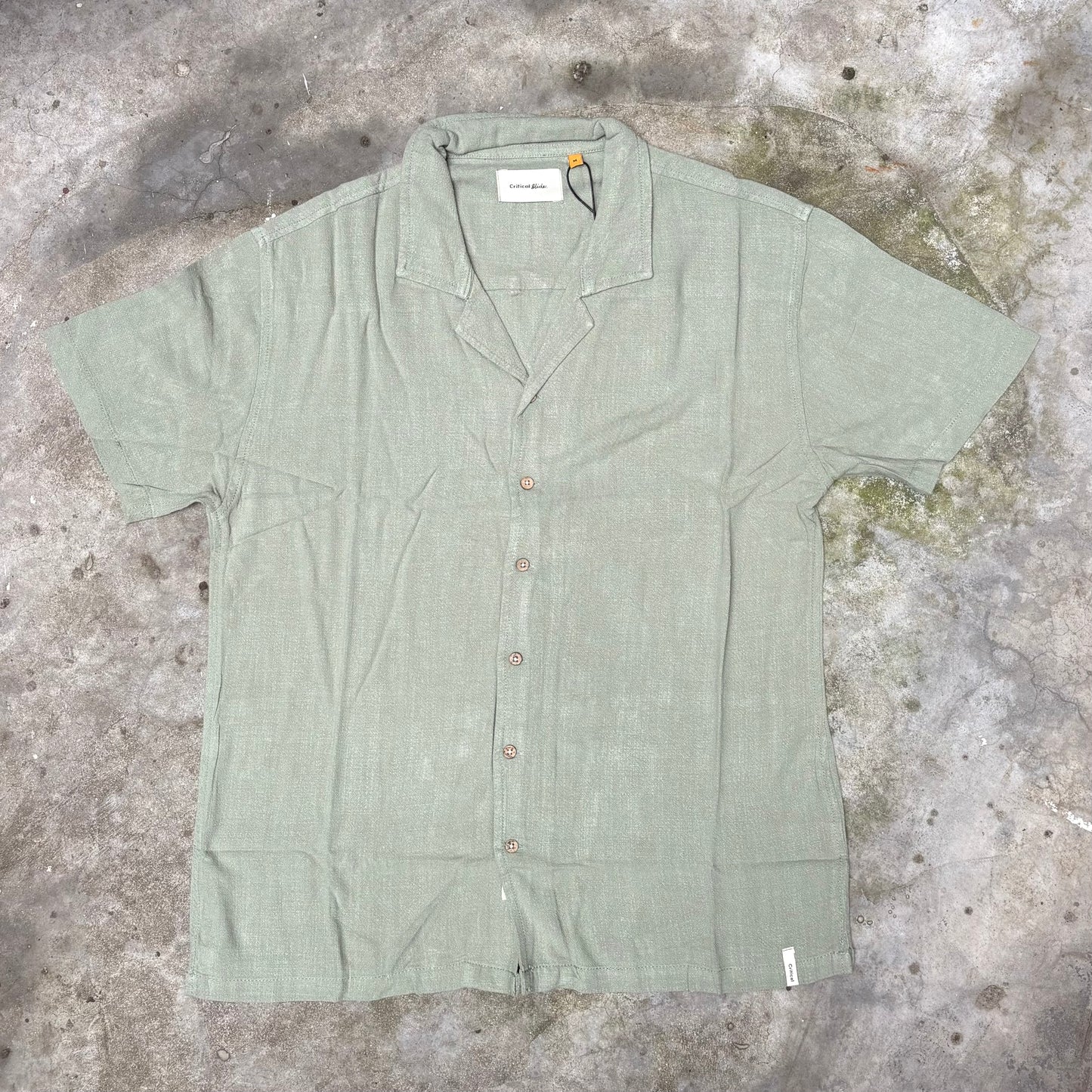 Green short-sleeve shirt on a textured concrete surface