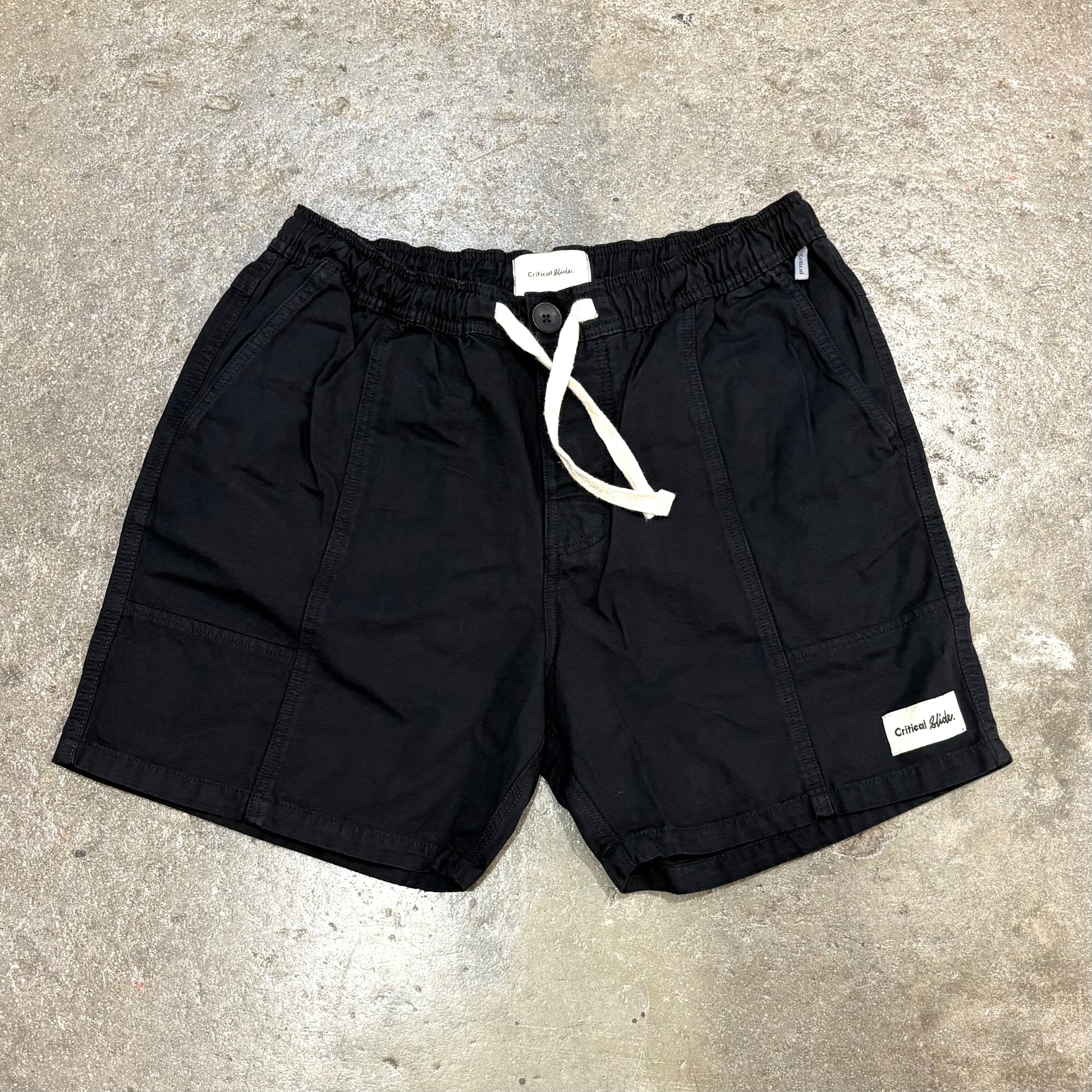 Black shorts with a white drawstring on a concrete surface