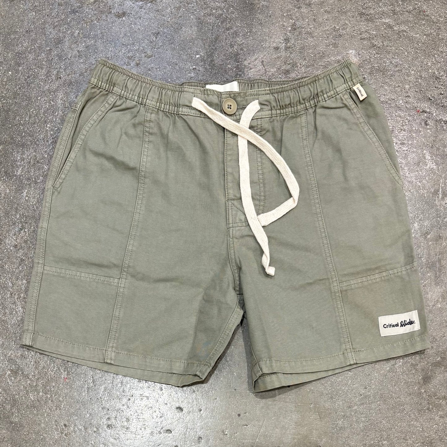 Green shorts with a drawstring on a gray concrete surface