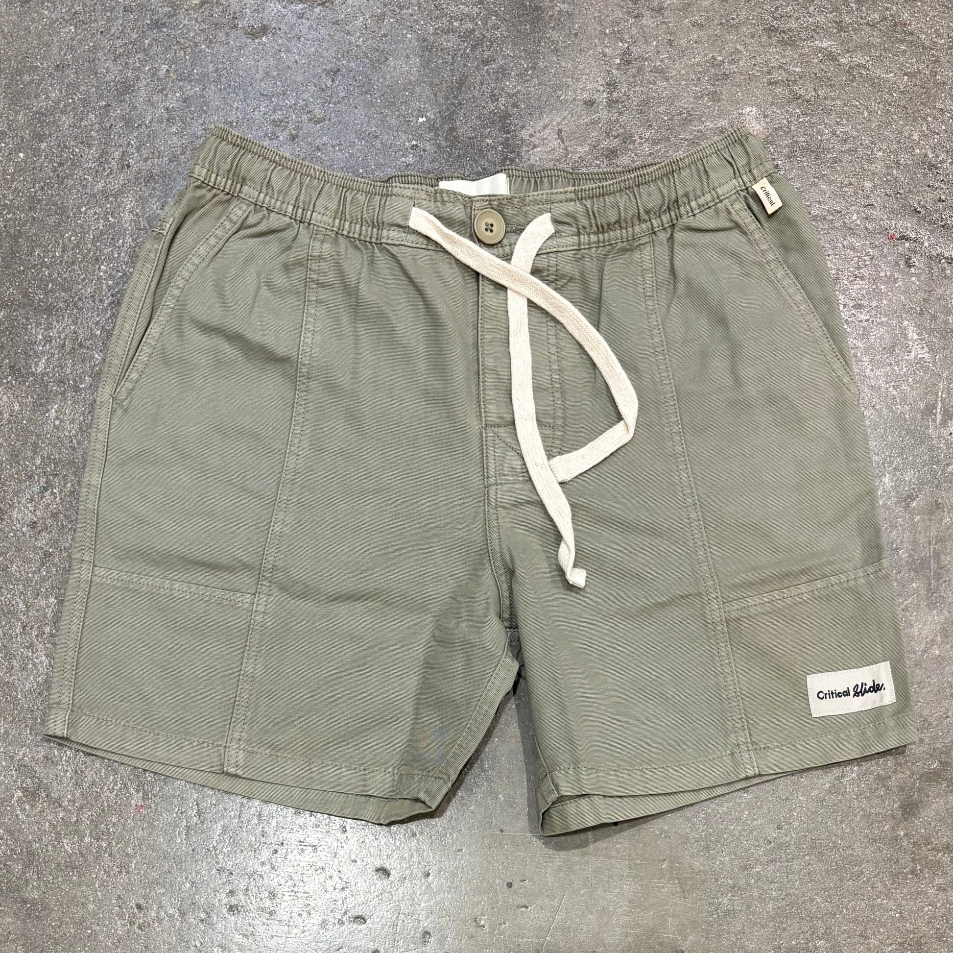 Green shorts with a drawstring on a gray concrete surface