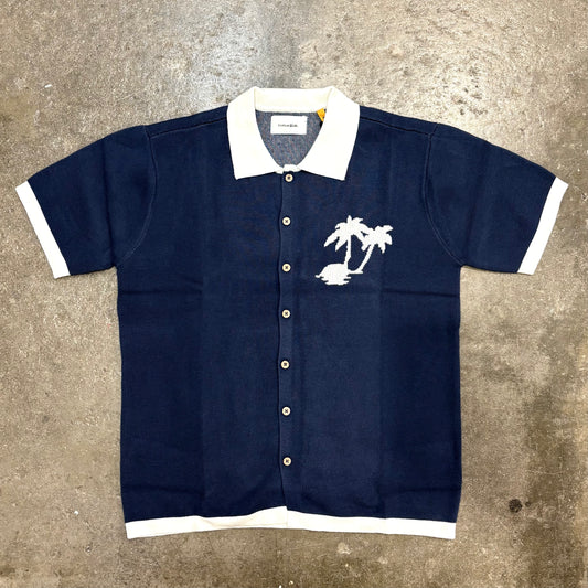 Navy blue shirt with white collar and palm tree design on a textured surface