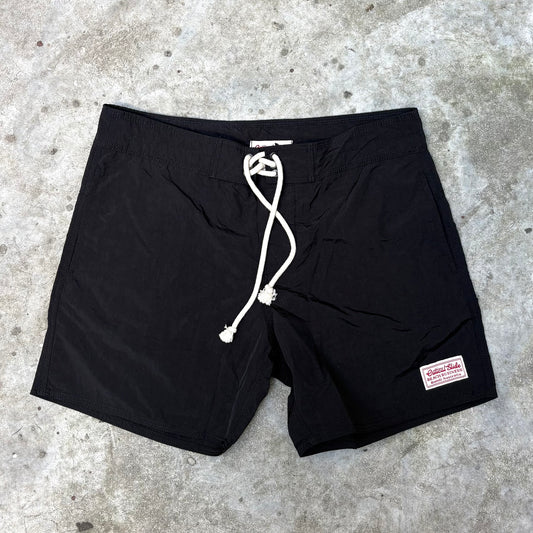 Black shorts with a brand label on a concrete surface