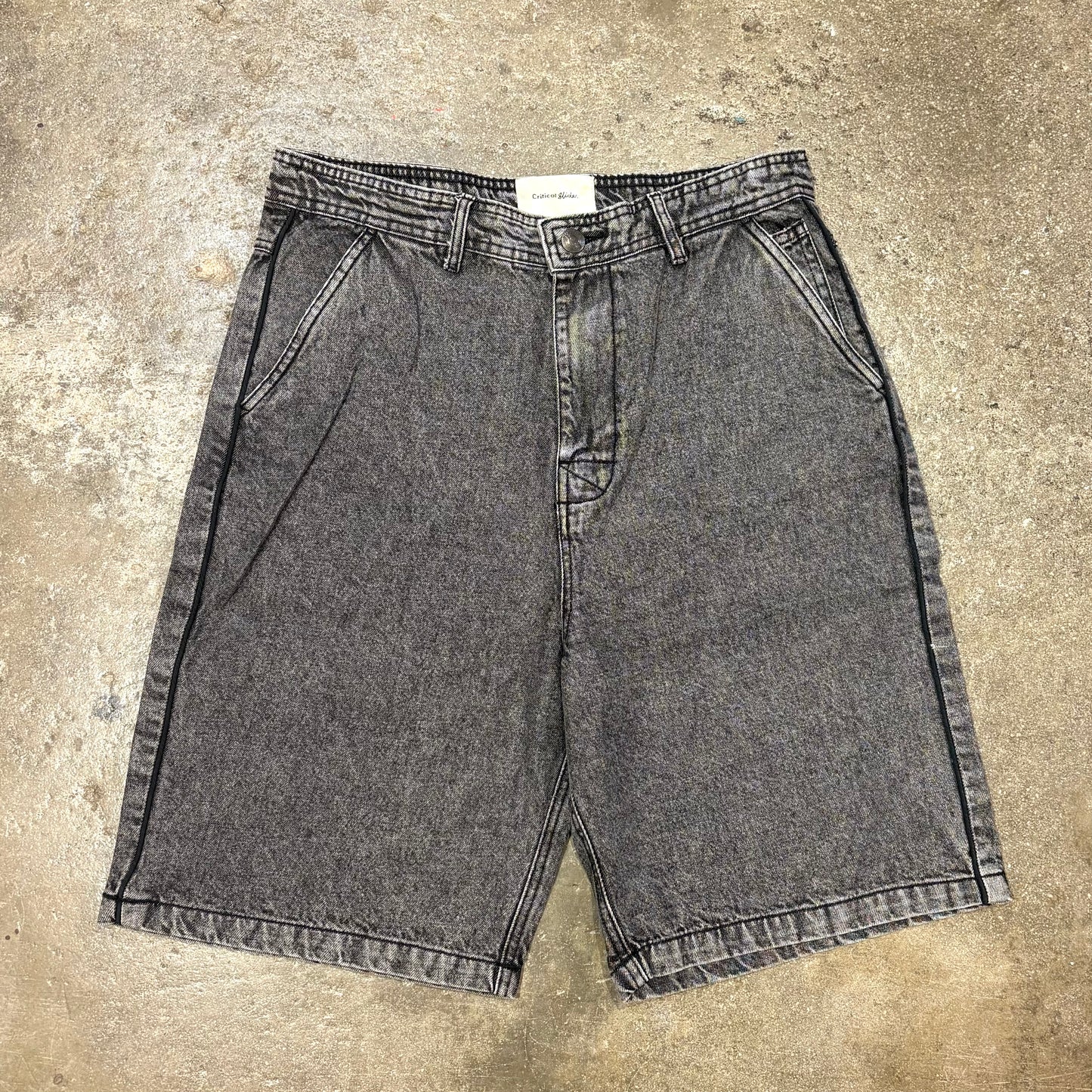 Pair of gray denim shorts on a concrete surface