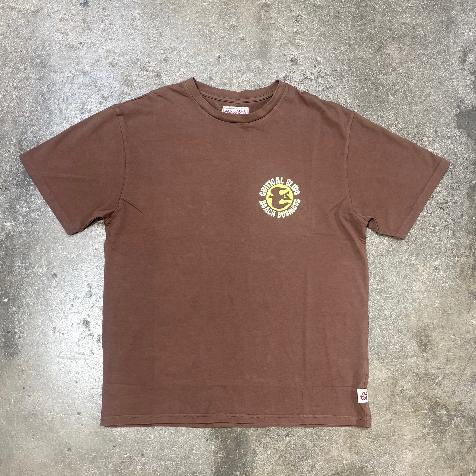Brown t-shirt with a logo on a gray concrete surface
