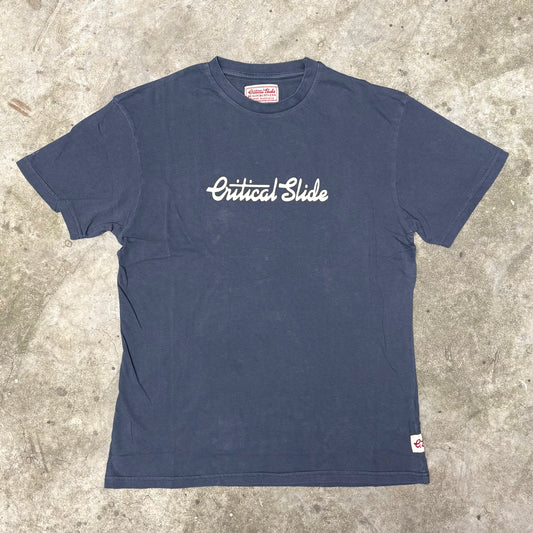 Navy blue t-shirt with 'Critical Slide' logo on a concrete surface