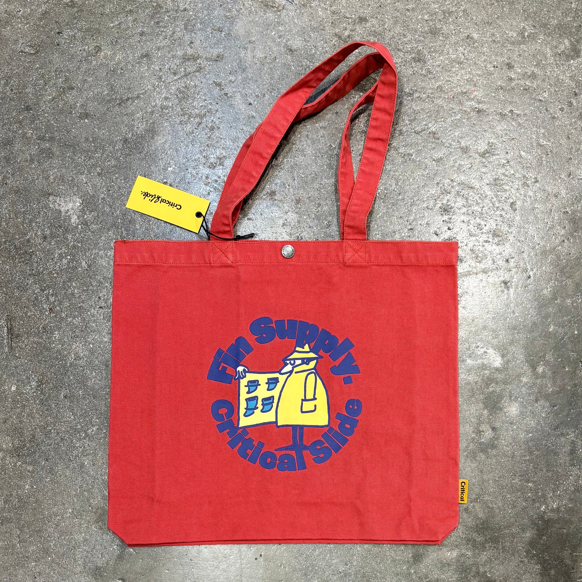 Red tote bag with a logo and text on a concrete surface