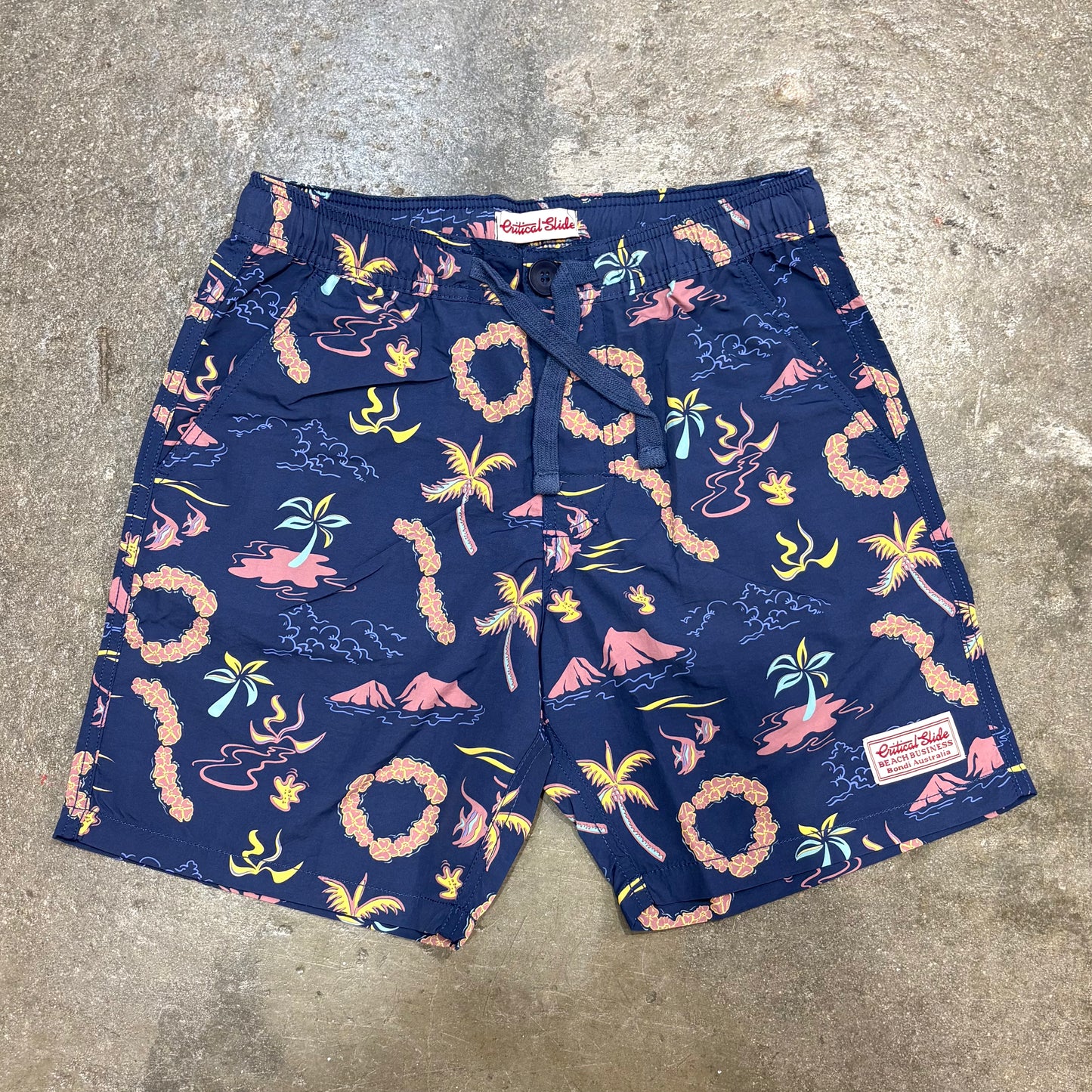 Navy blue shorts with tropical pattern on a concrete floor