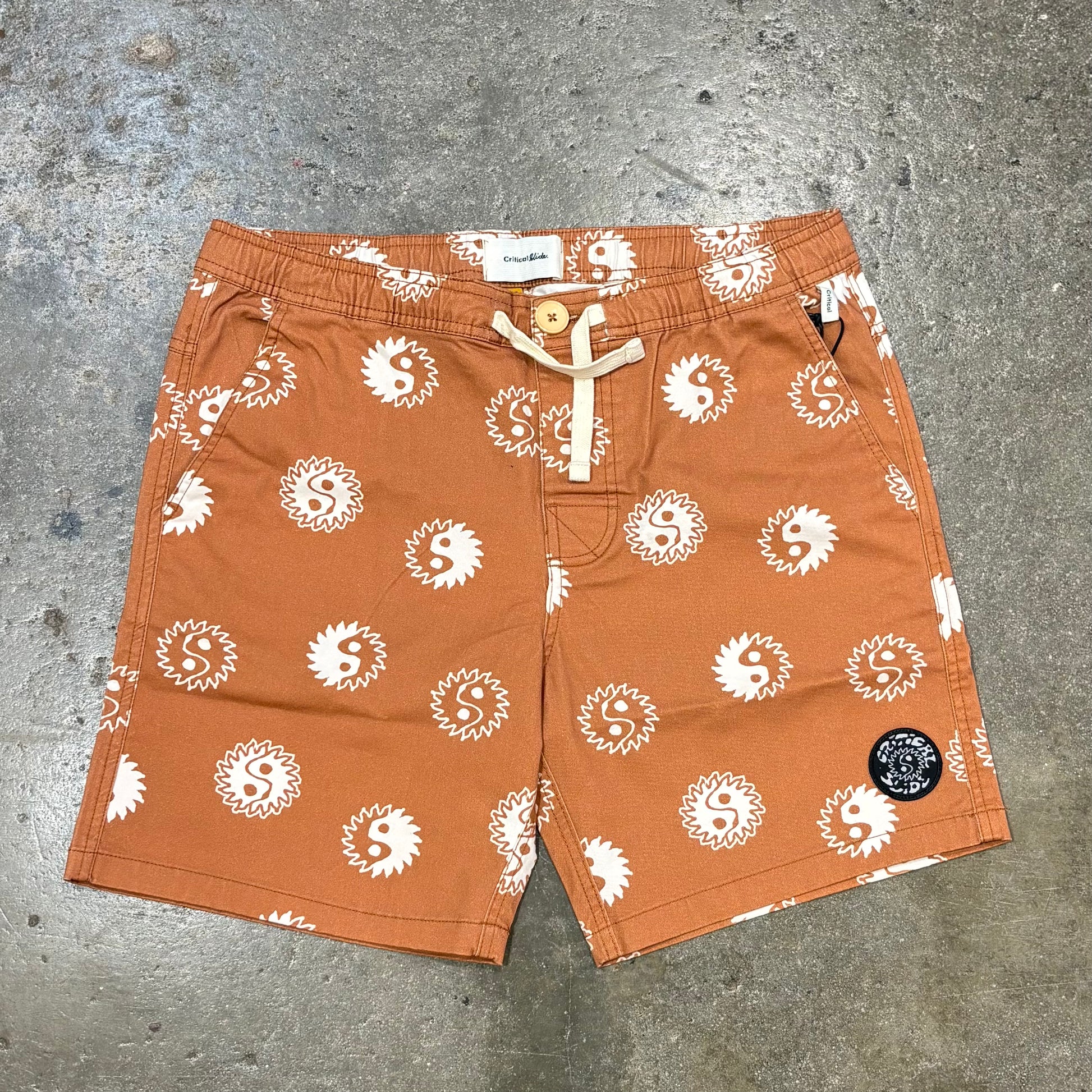Orange shorts with white patterns on a gray concrete surface